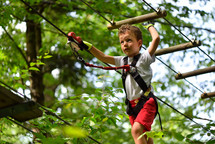Kids climbing and playing at adventure park holding ropes and climbing wooden stairs