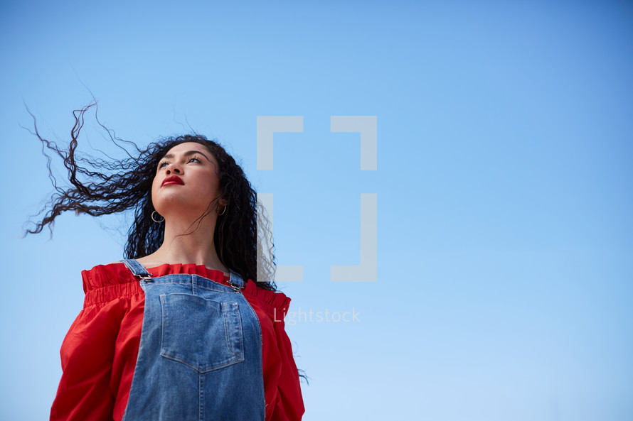 portrait of a woman standing outdoors against a blue sky 