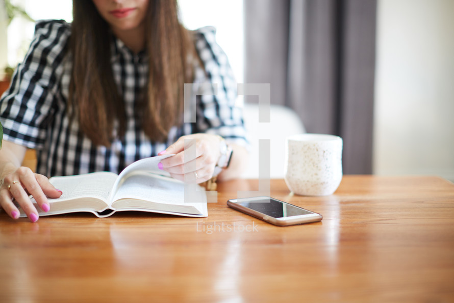 a woman sitting at a desk reading a Bible 