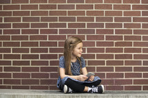 a girl child sitting on a bench listening to an iPod 