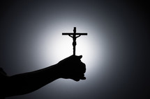Silhouette photo - praying hands holding a crucifix
