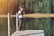Creative child, kid photographer (a little boy) with a camera taking landscape pictures near la lake