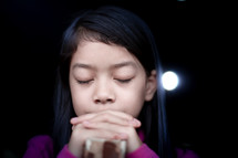 a closeup of a girl child praying in an open window 