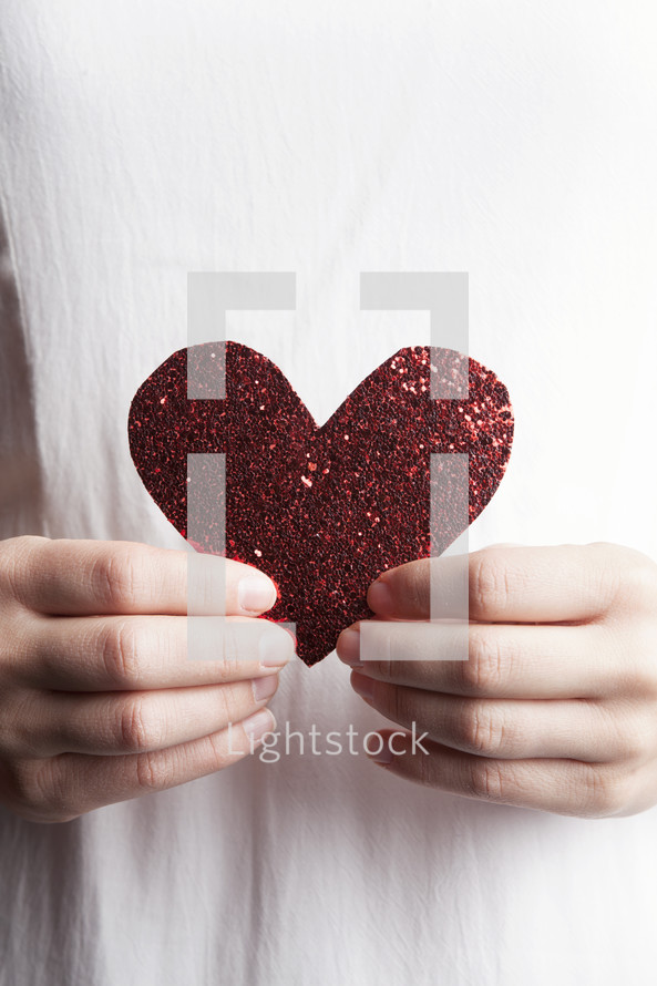 Woman's hands holding a glittery heart.
