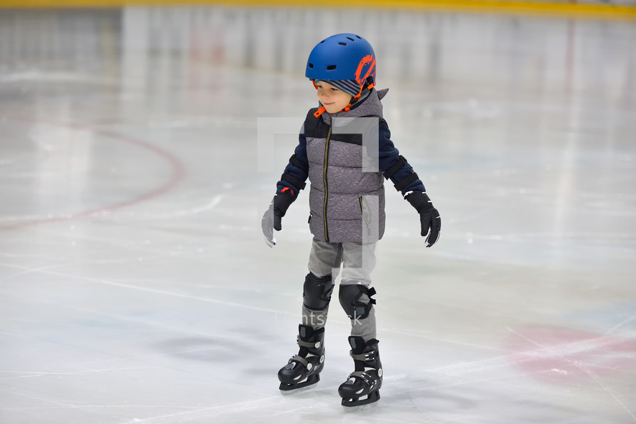child ice skating in a helmet 