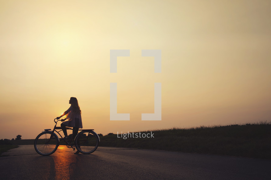 woman riding a bicycle at sunset 
