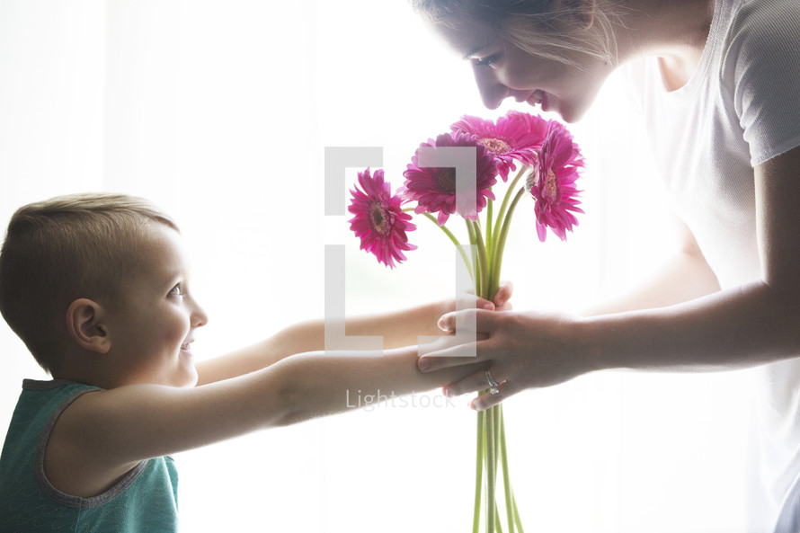 a boy giving his mother flowers 