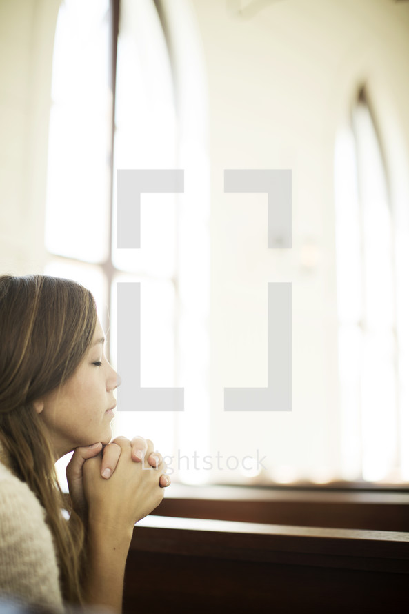 a woman with praying hands at church 