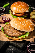 A burger on a stone board on a table. On a black background. High quality photo