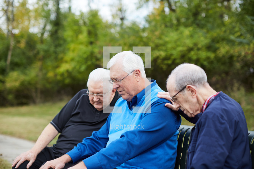 elderly men praying outdoors 