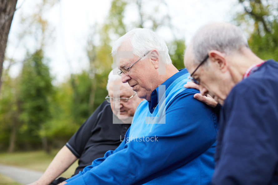 elderly men praying outdoors 