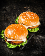 A burger on a stone board on a table. On a black background. High quality photo