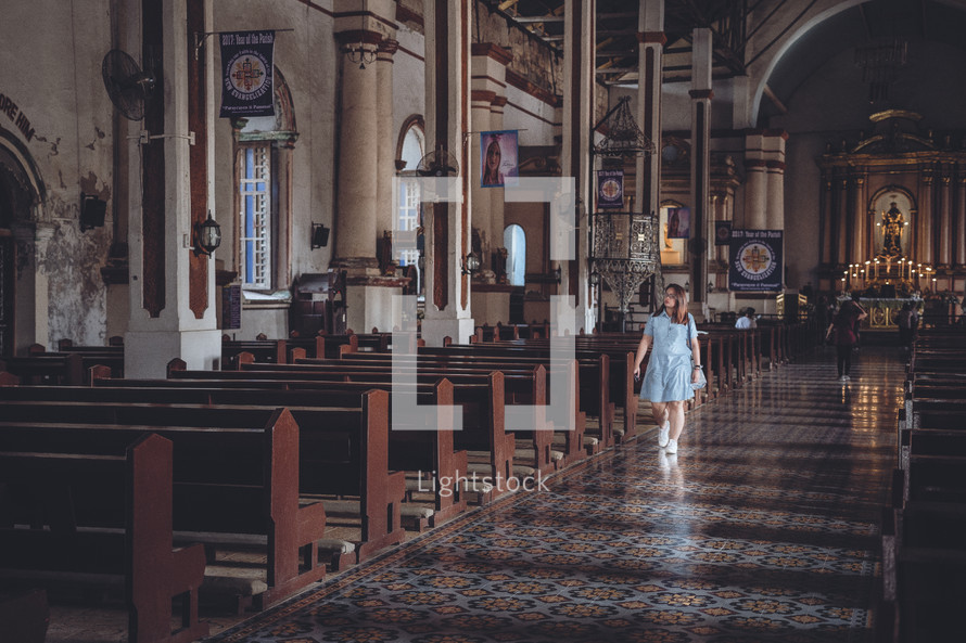 a woman walking down the aisle of a Catholic church 