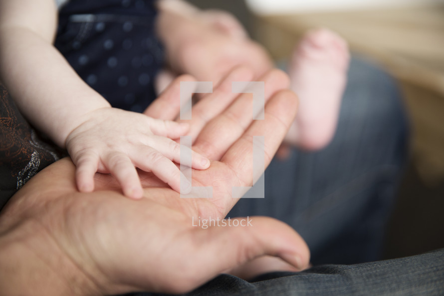A baby's hand on a mother's hand.
