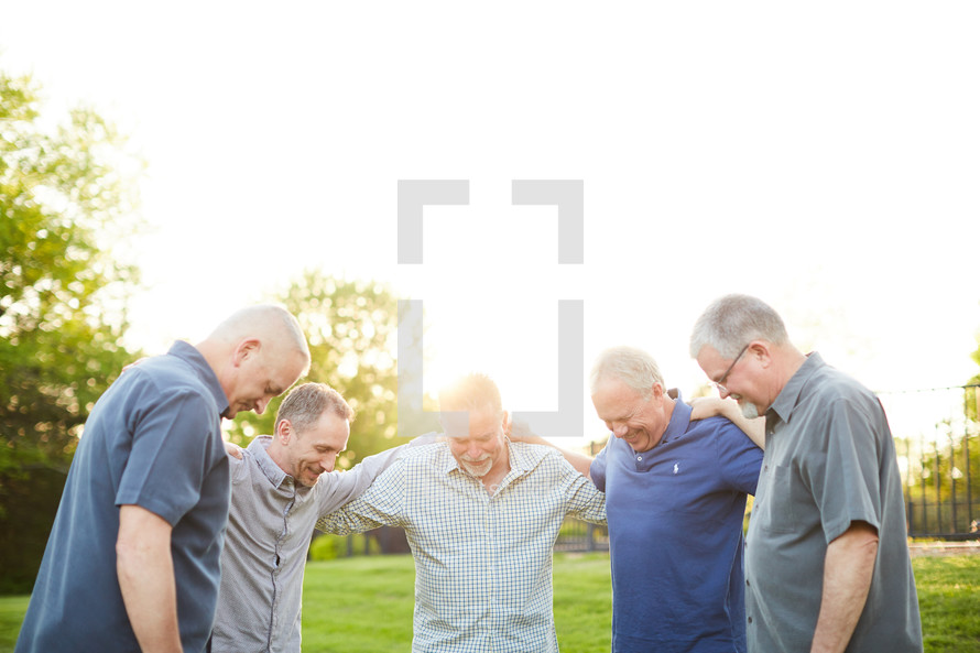 men praying together outdoors 