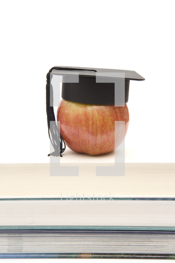 graduation cap on an apple on a stack of books 