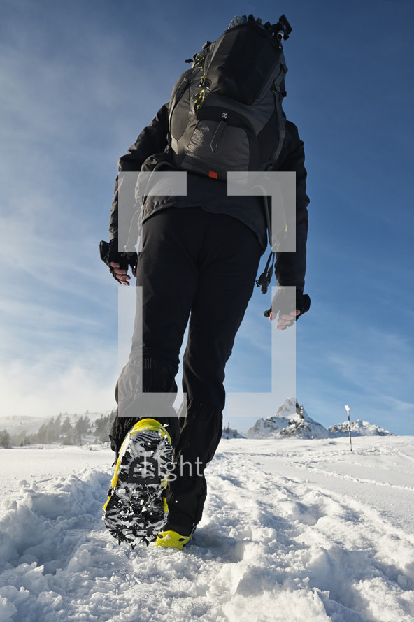 Man Walking On Snow With Shoe Spikes In Winter Time