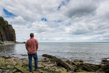 man standing on a shore taking in the view 