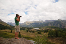 a man with a camera taking a picture of mountains 