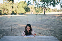 woman reading a Bible at a picnic table 