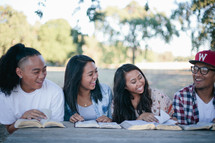 friends reading Bibles together outdoors at a picnic table 