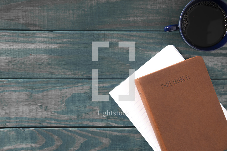 leather Bible, notebook, and coffee cup on a wood background 