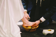 A groom washing his brides feet. 