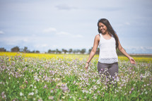 Woman walking through a field of flowers.