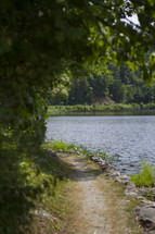 A view down a stone path along a lake.