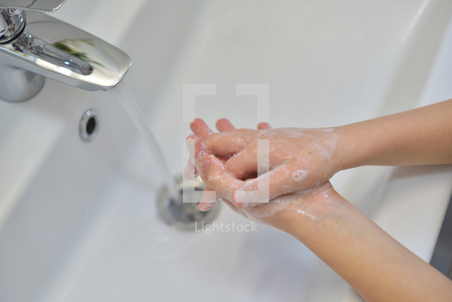washing hands with soap in a sink 