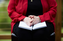 woman with her hands on a Bible in her lap 