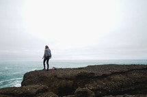 a woman standing on cliffs along a shore 