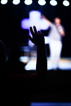 silhouettes of people with hands raised at a worship service 