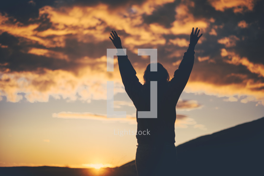 silhouette of a woman with raised hands