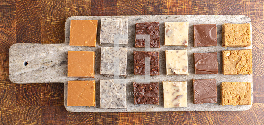 Chocolate fudge dessert squares on stone board on wood table