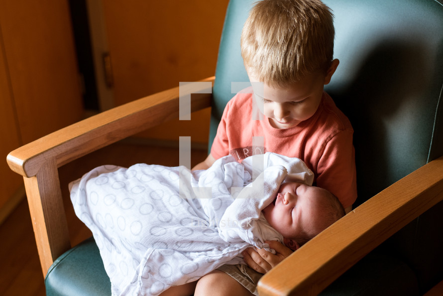 a child holding his newborn sibling 