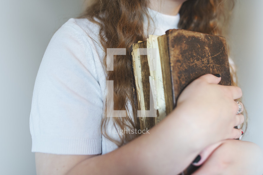 an old weathered leather Bible in young girls arms
