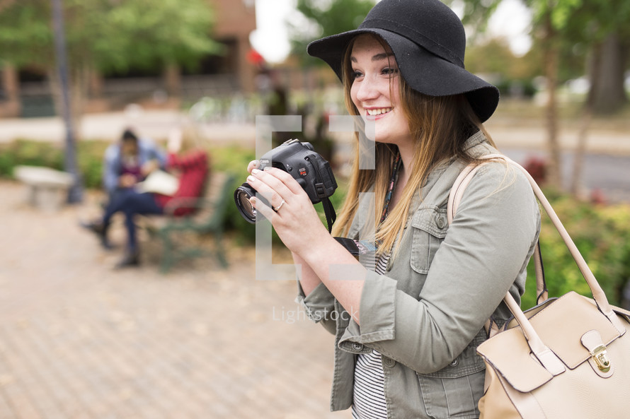 a young woman with a camera standing on a college campus 