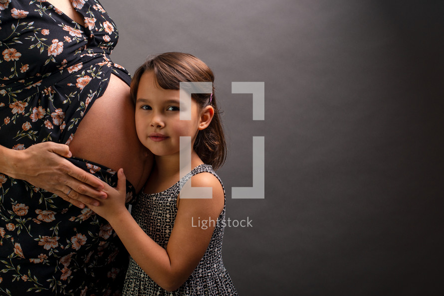 girl hugging her pregnant mother 