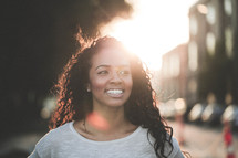 a smiling young African-American woman outdoors under intense sunlight 