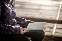 a girl reading a Bible outdoors 