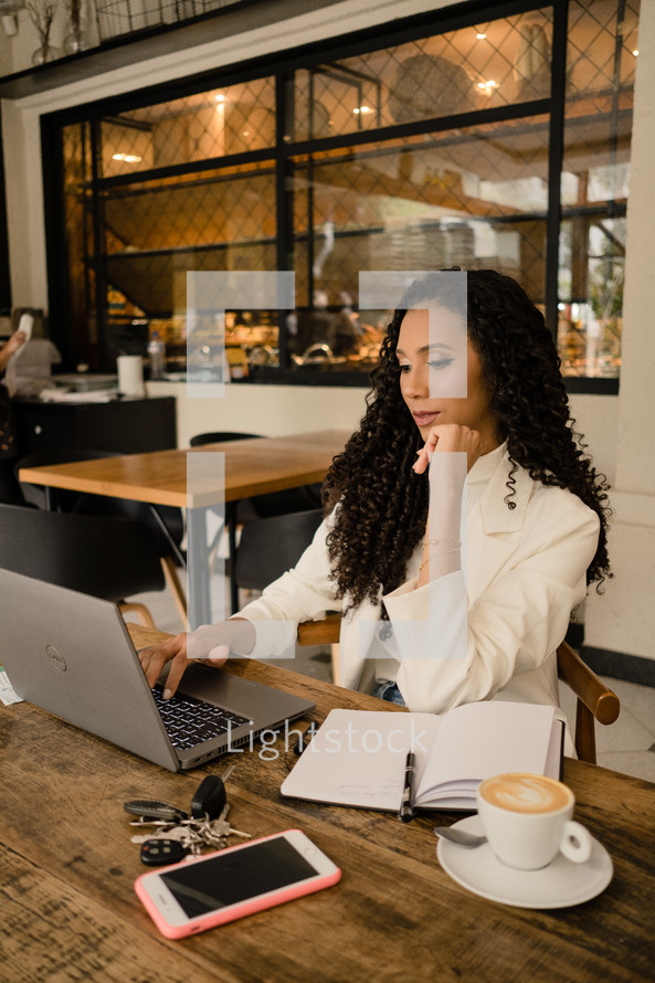 a woman working on a laptop at a cafe 