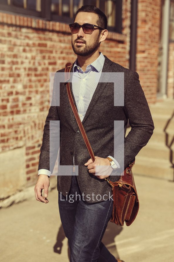 a man in a blazer carrying a satchel, walking to work 