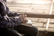 a girl praying over a Bible outdoors 