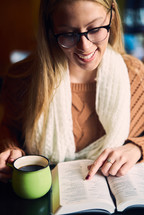a woman reading a Bible and a coffee cup