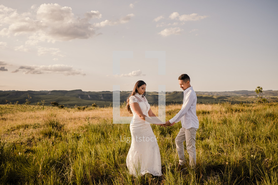 bride and groom standing in a field 