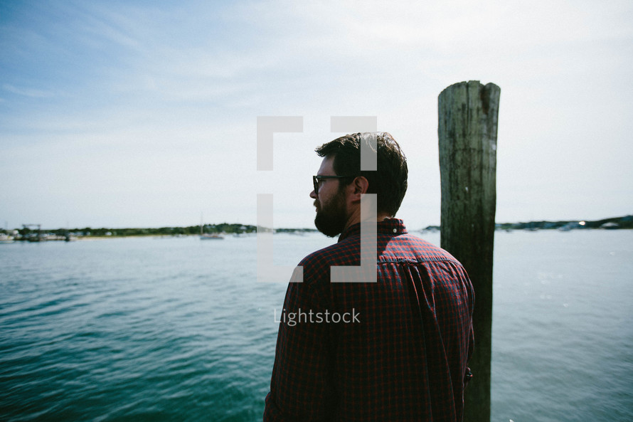 a man standing on a dock looking out at the harbor 