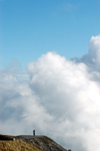 man standing at the edge of a cliff in the clouds 