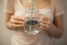 A woman holding a cup of water that says John 4:14