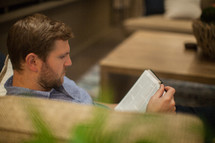 A man sitting on a couch reading the Bible